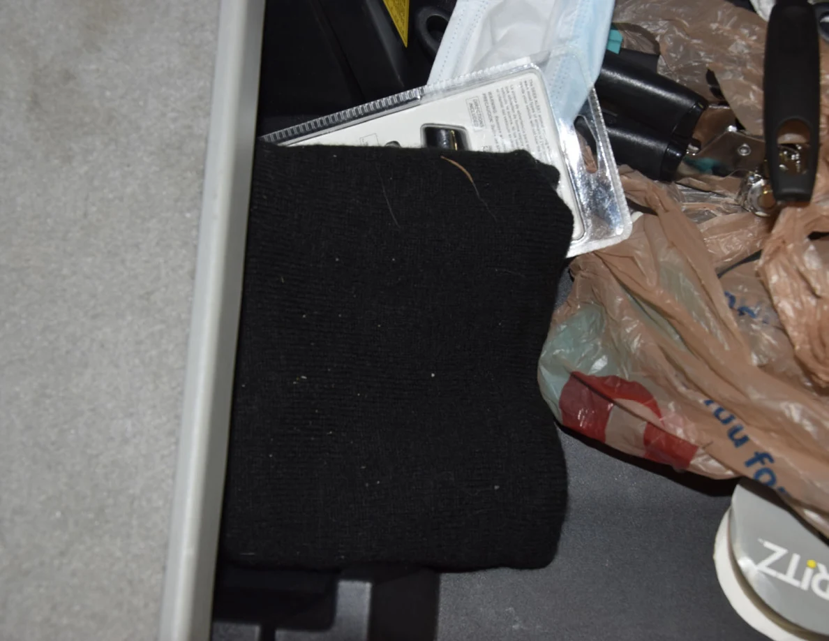 Black knit fabric beside packaging, shopping bags and a disposable face mask in storage.