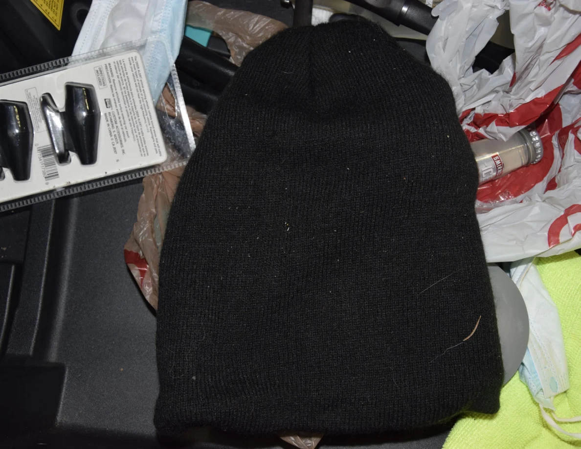 Close view of a black knit cap among plastic bags and packaged items.