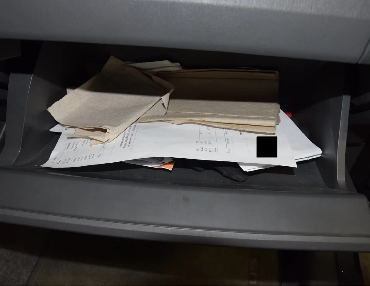Angled view of brown napkins and stacked papers inside an open glove compartment.