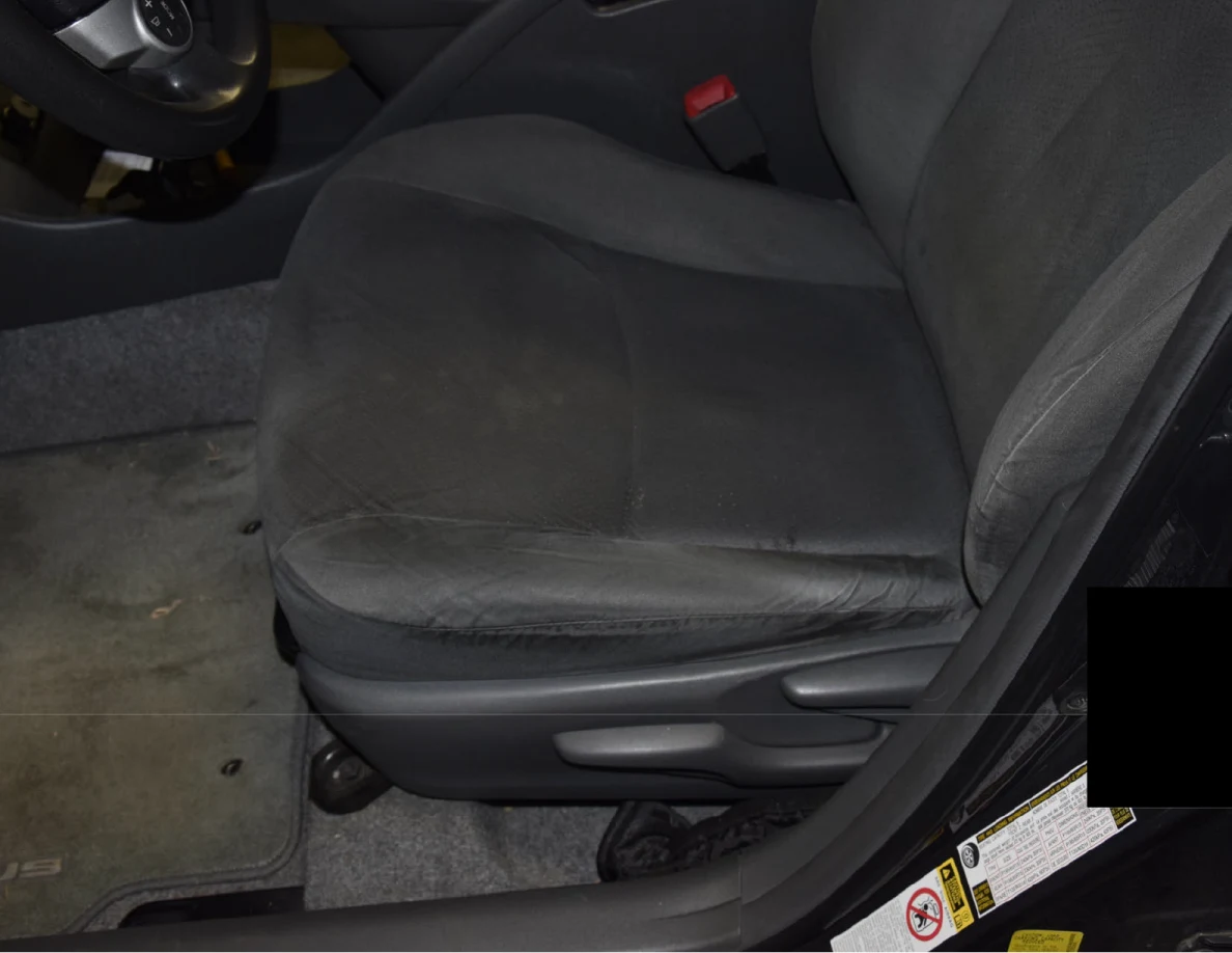 Gray fabric driver-seat cushion beside the center console, floor mat and door sill.