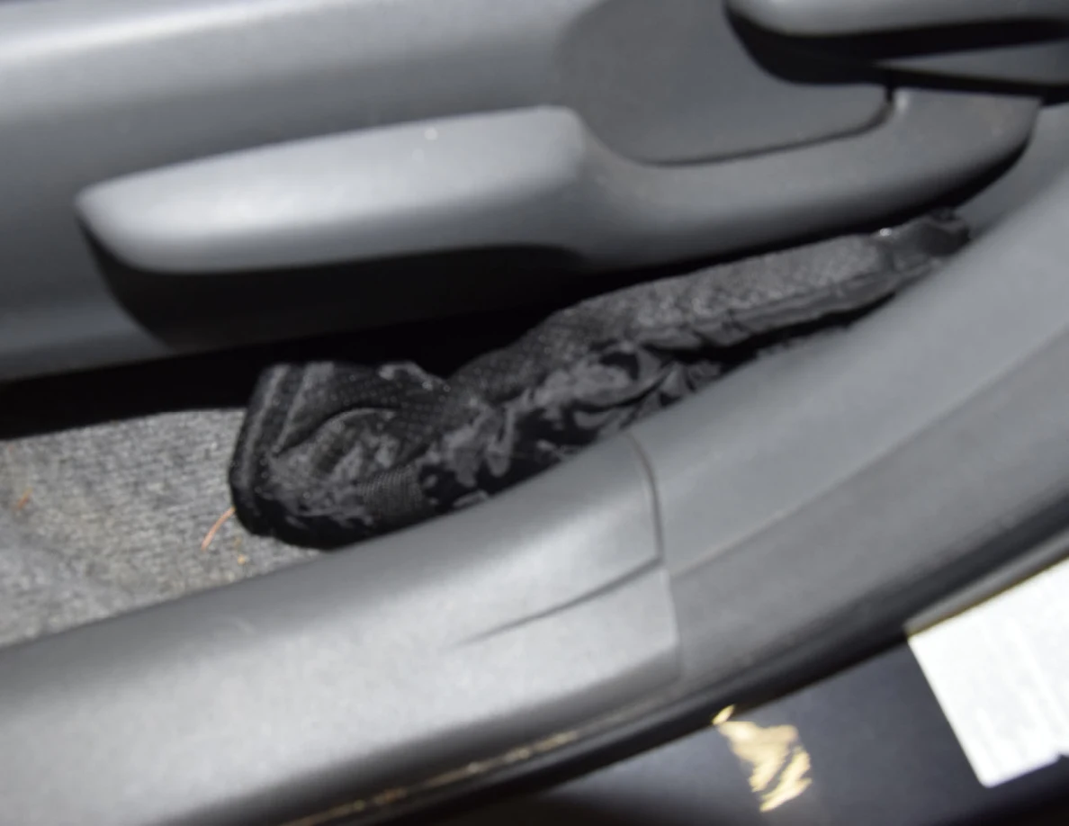 Closer view of a black glove beside a car-seat adjustment lever.