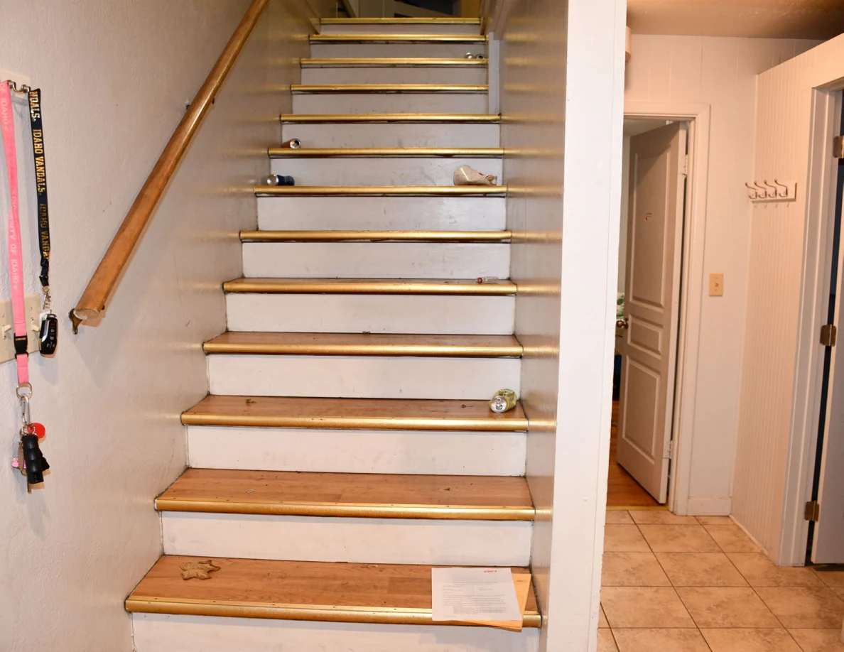 Wooden staircase with white risers, scattered small items and papers on a lower step.
