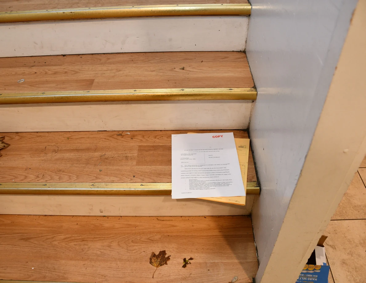 Lower wooden stairs with a printed document on a yellow envelope.