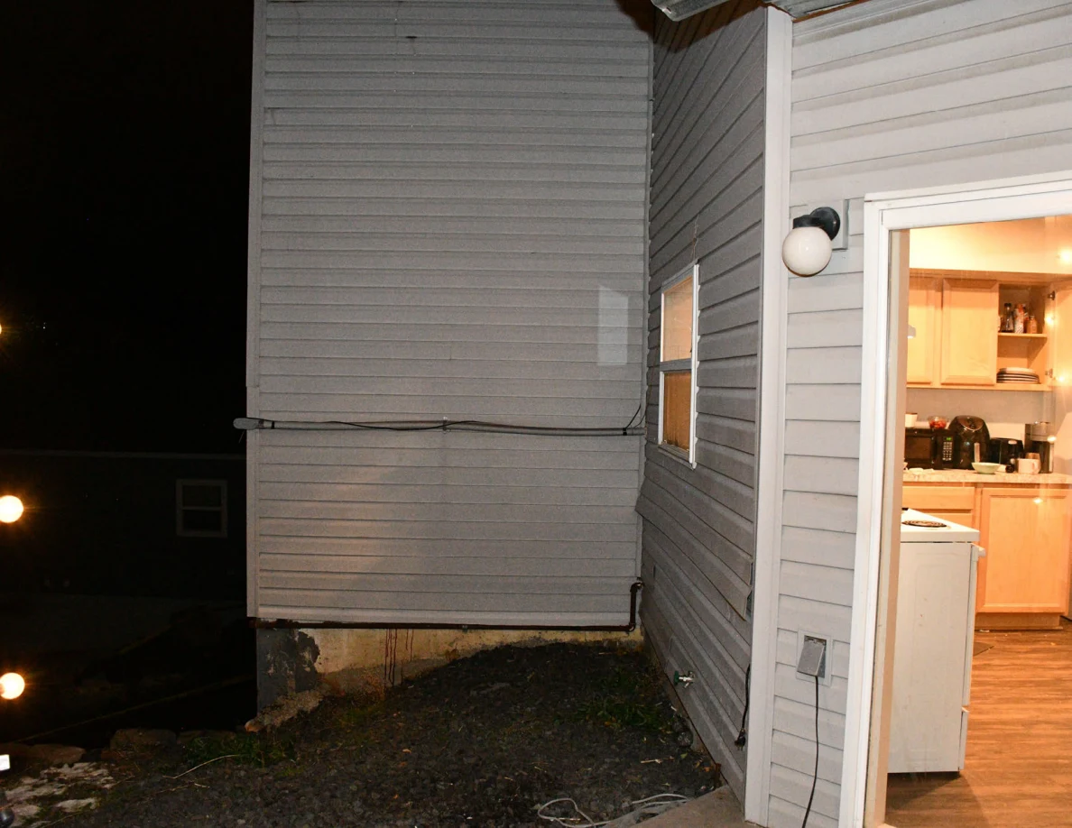 Exterior wall and an open kitchen doorway at night, with cabinets visible inside.
