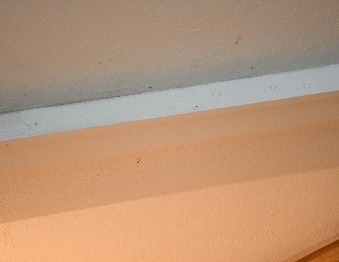 Small reddish marks around white trim above a stair opening.
