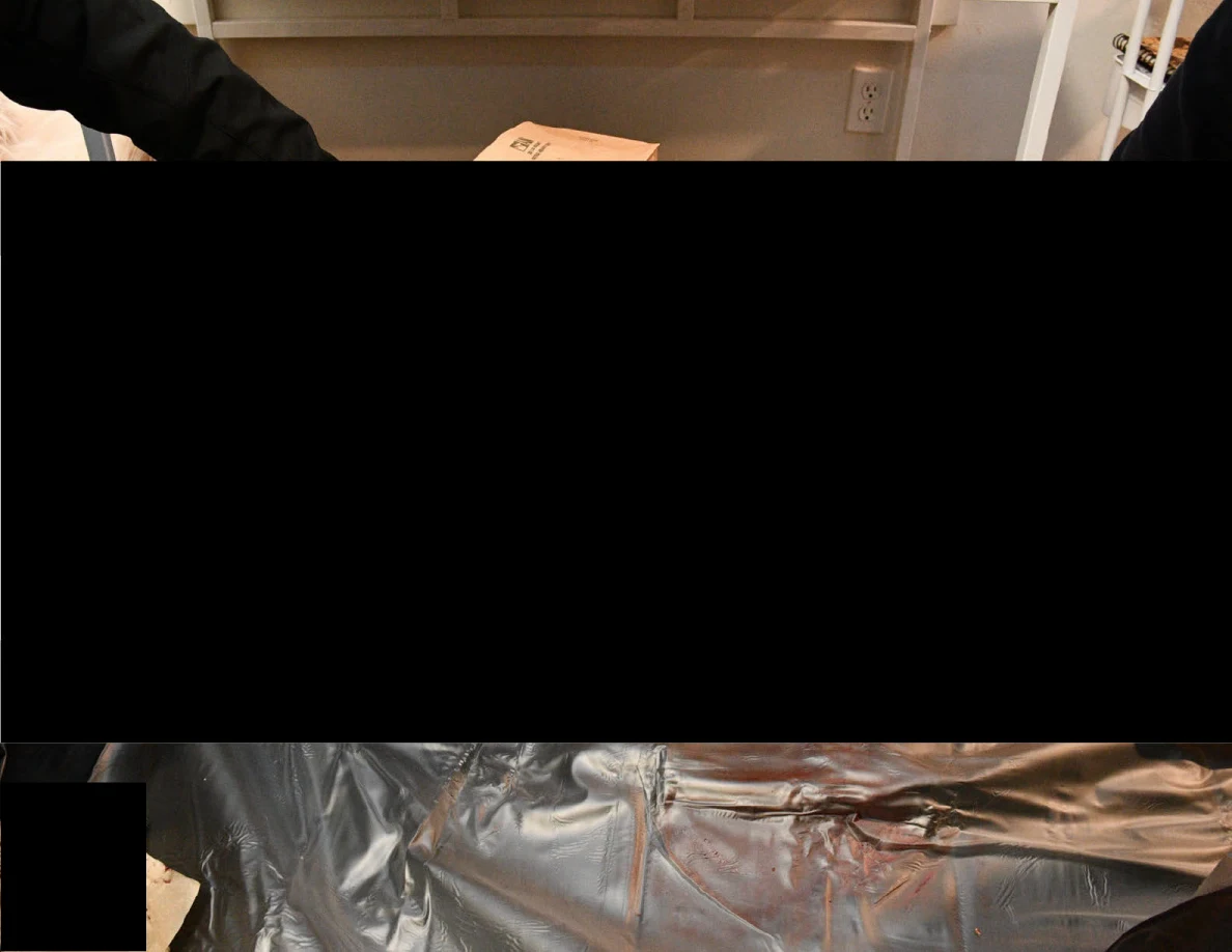 Mostly blacked-out photograph with a reflective silver surface visible along the lower edge.