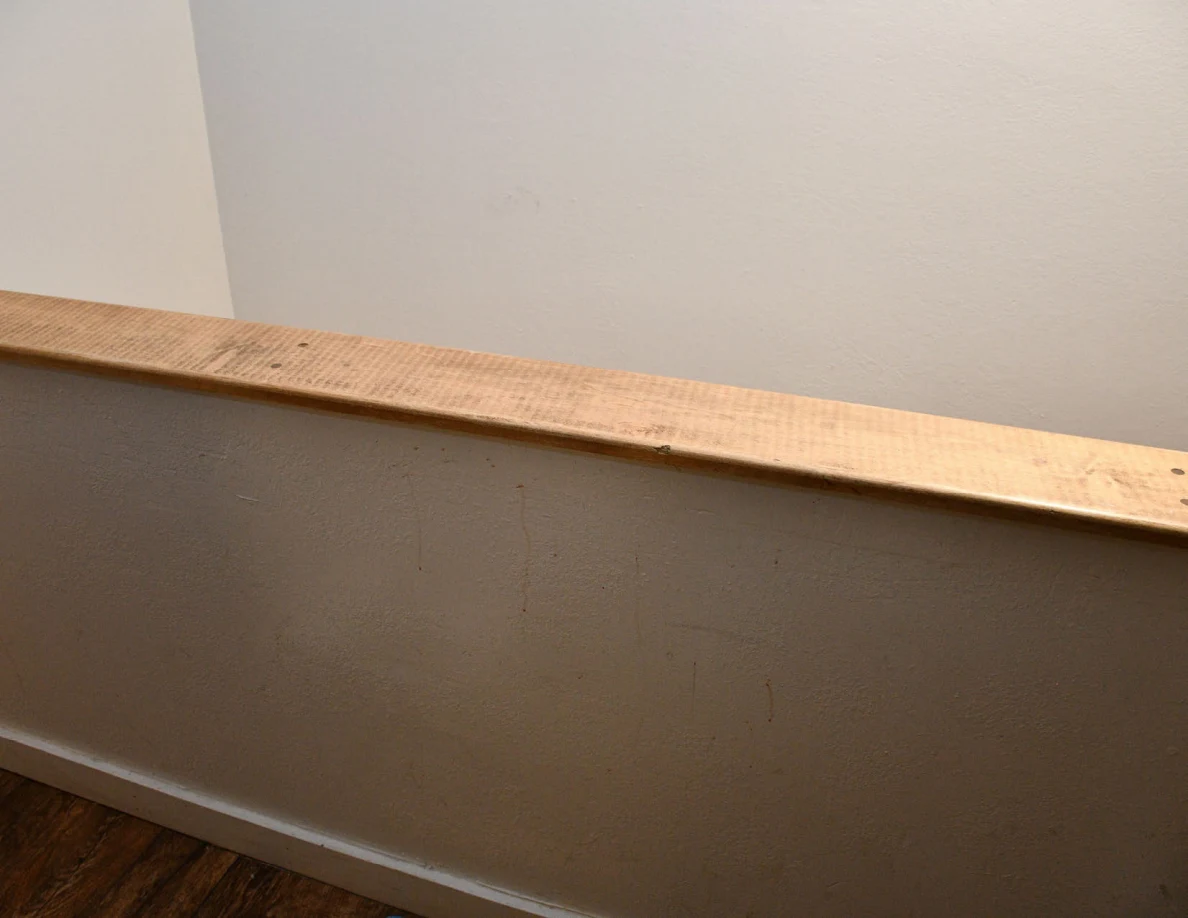 Wide view of a wood-capped half-wall with faint marks below the cap.
