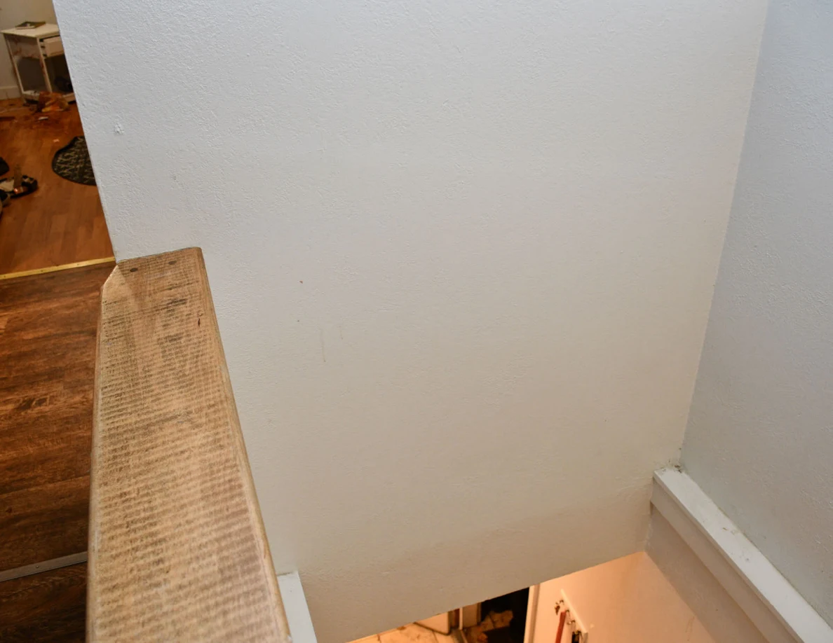 Stairwell corner with a wood-capped half-wall and pale wall.