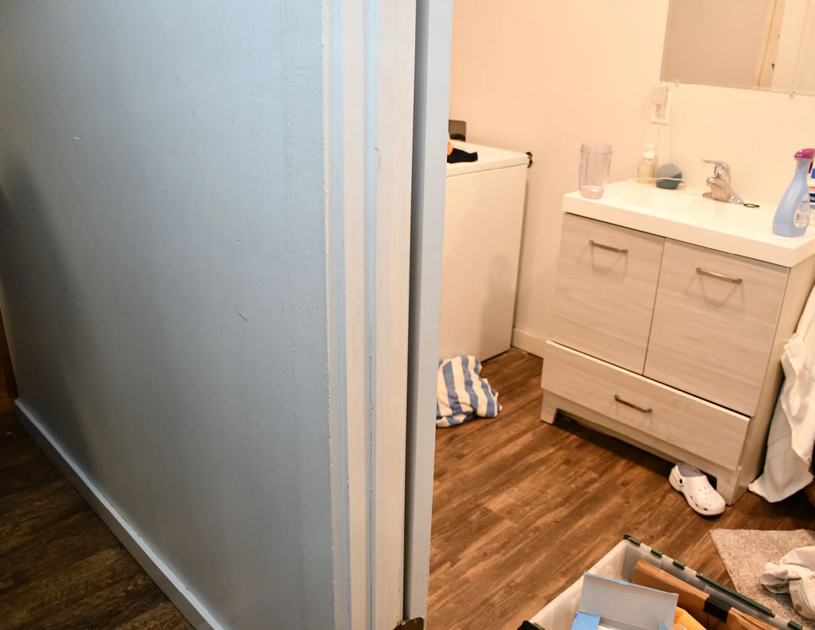 Open bathroom doorway with vanity, sink, cleaning bottle and wood-look floor.