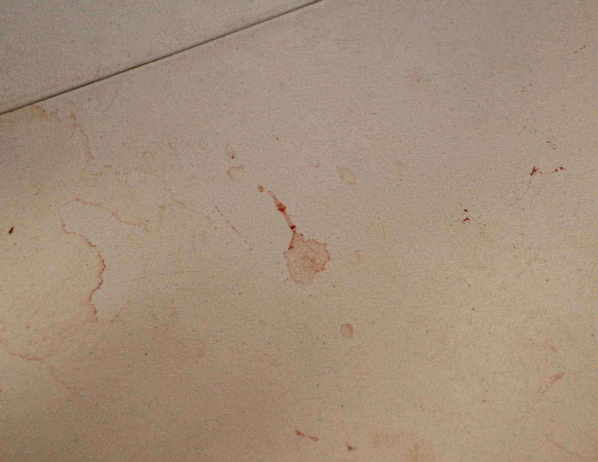 Close view of reddish streaks and ring-shaped marks on a white tabletop.