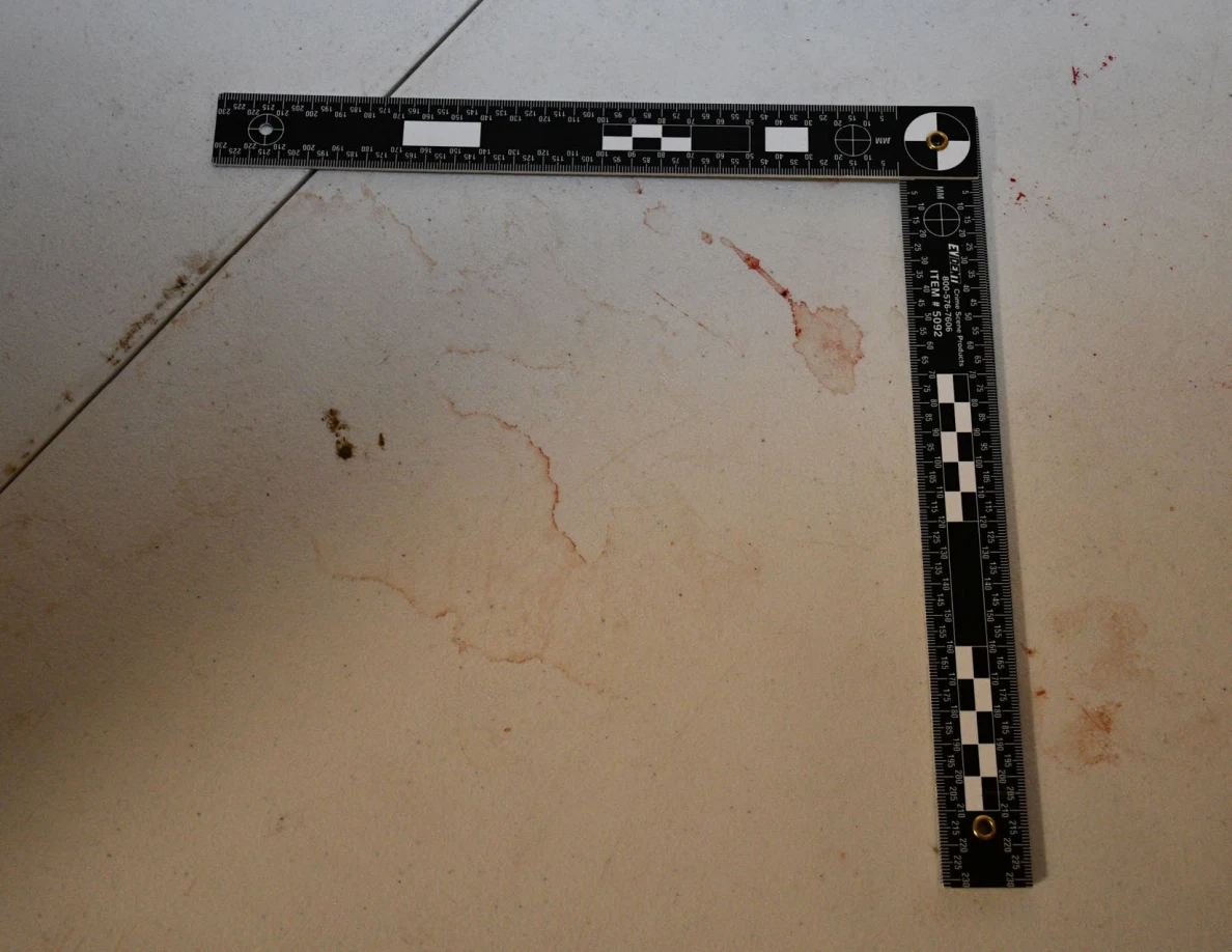 L-shaped ruler beside reddish marks and ring-shaped outlines on a white tabletop.