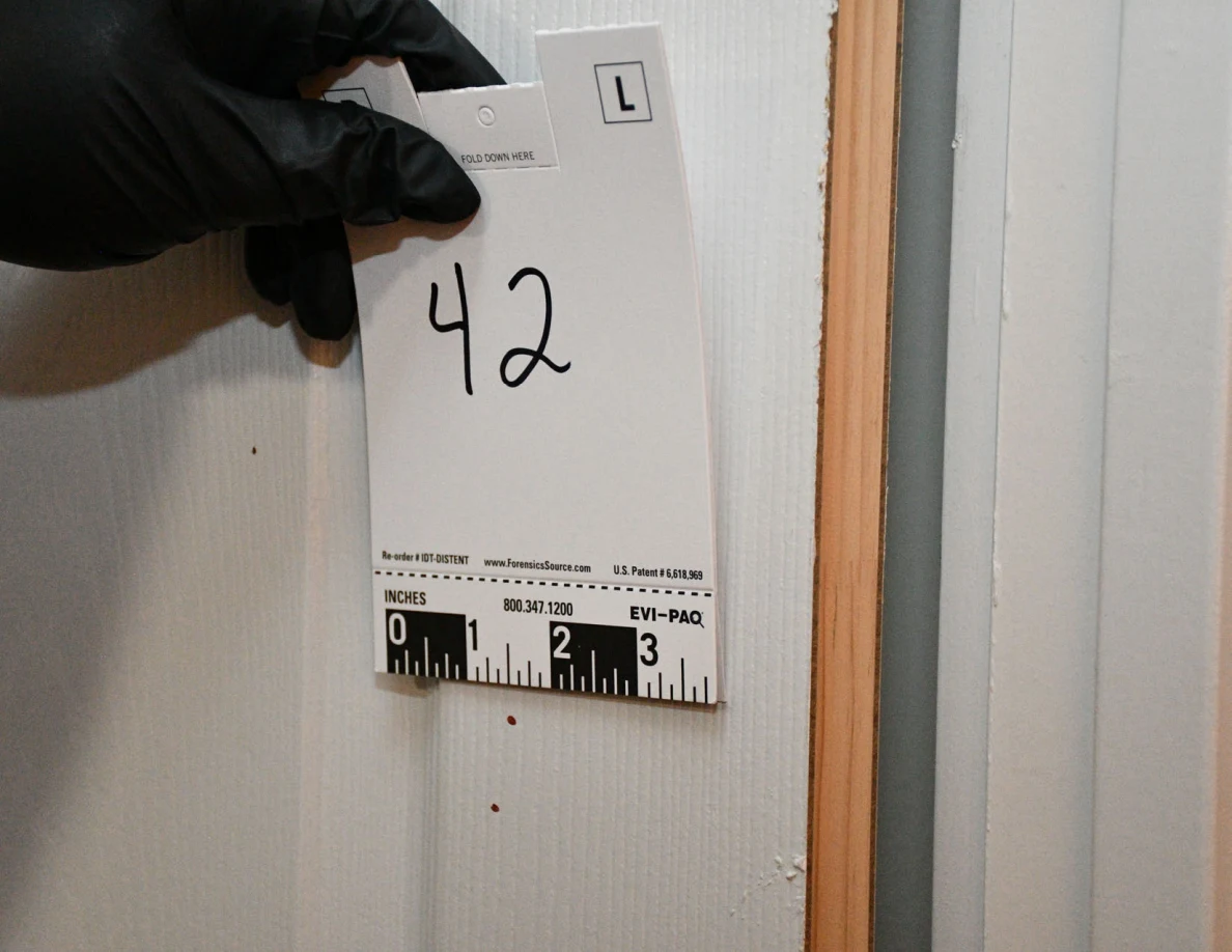 Card 42 held beside small reddish spots on a white panel door.