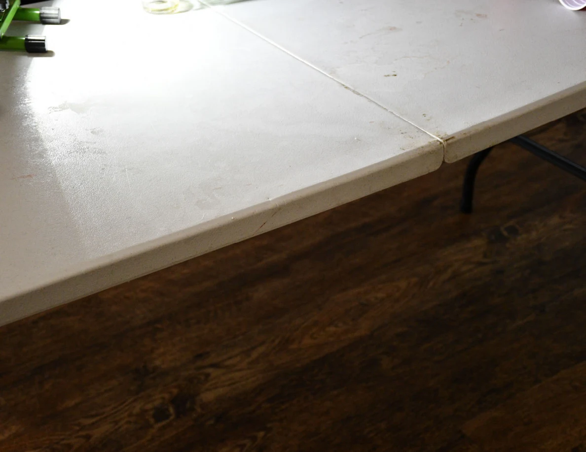 White folding table surface and edge above wood-look flooring.