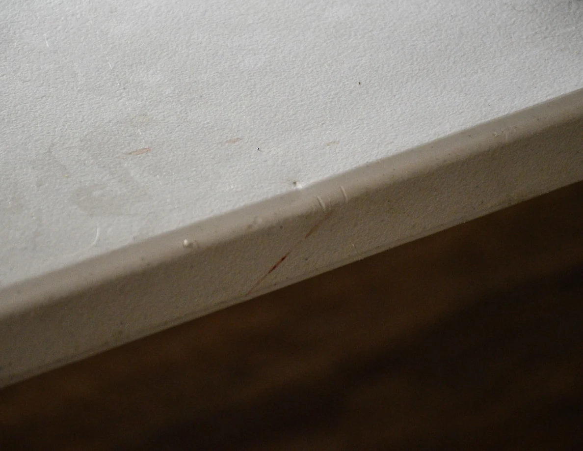 Close view of a faint reddish streak along the edge of a white folding table.