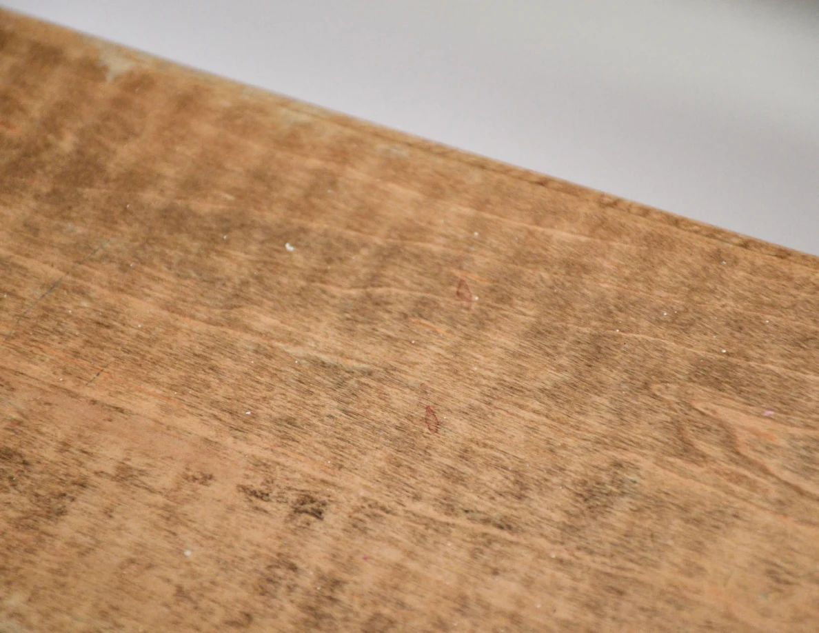 Close view of scuffed wood grain and a faint reddish mark on a half-wall cap.