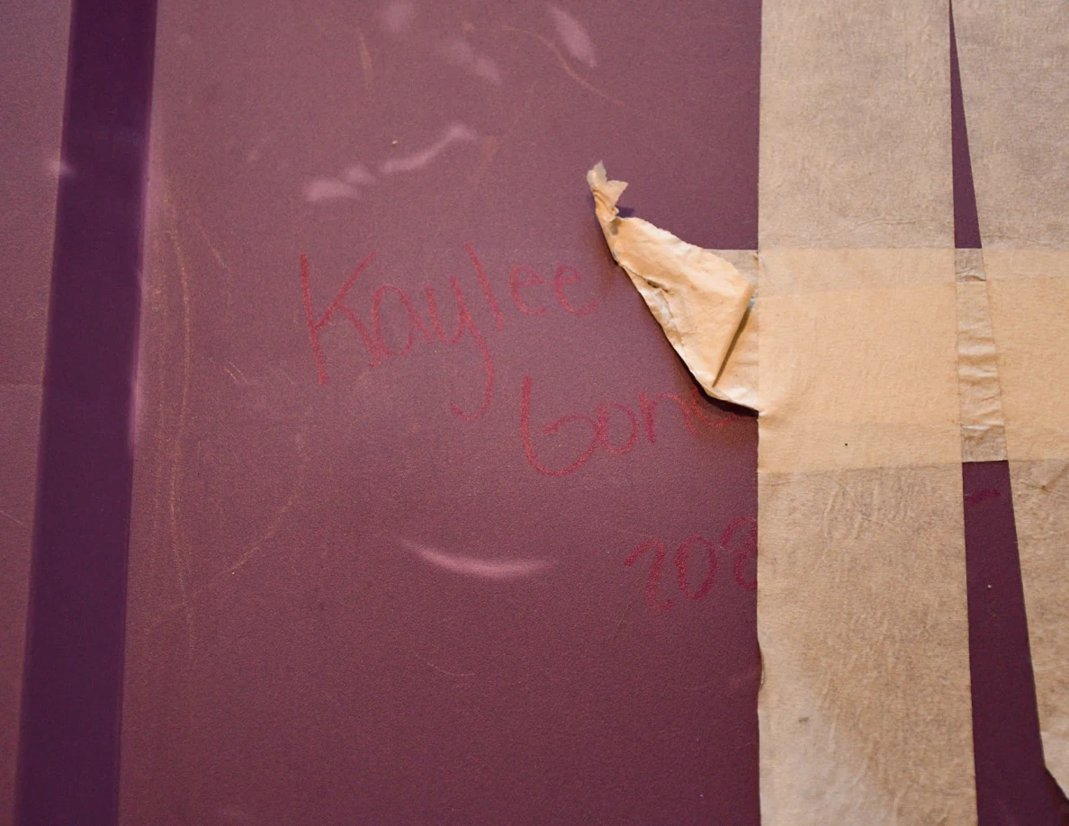 Close view of a purple tote lid with masking tape and faint handwriting.