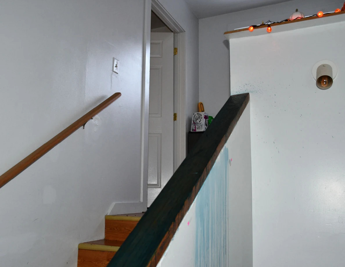 Wooden stairs and dark-capped half-wall leading to a landing with orange decorative lights.