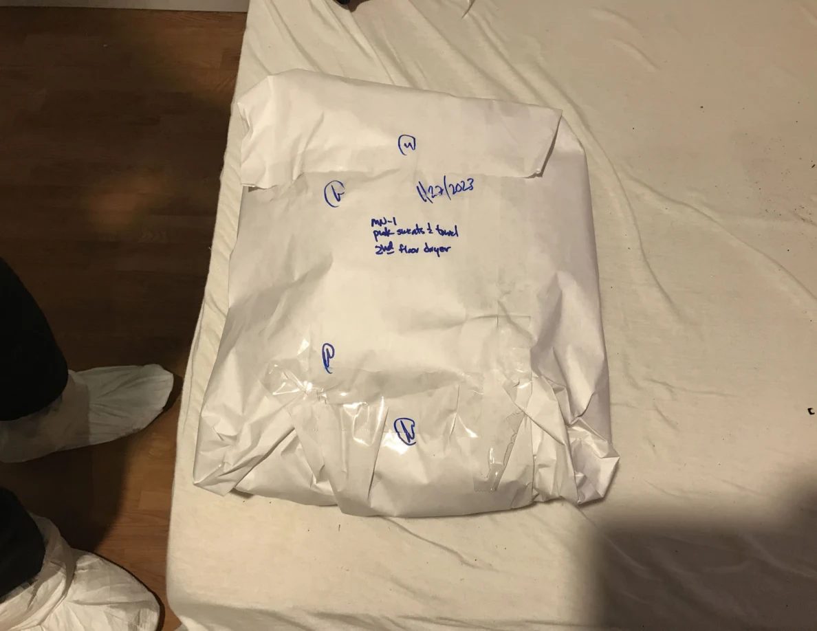 Large folded white-paper package sealed with clear tape and blue handwritten notes.