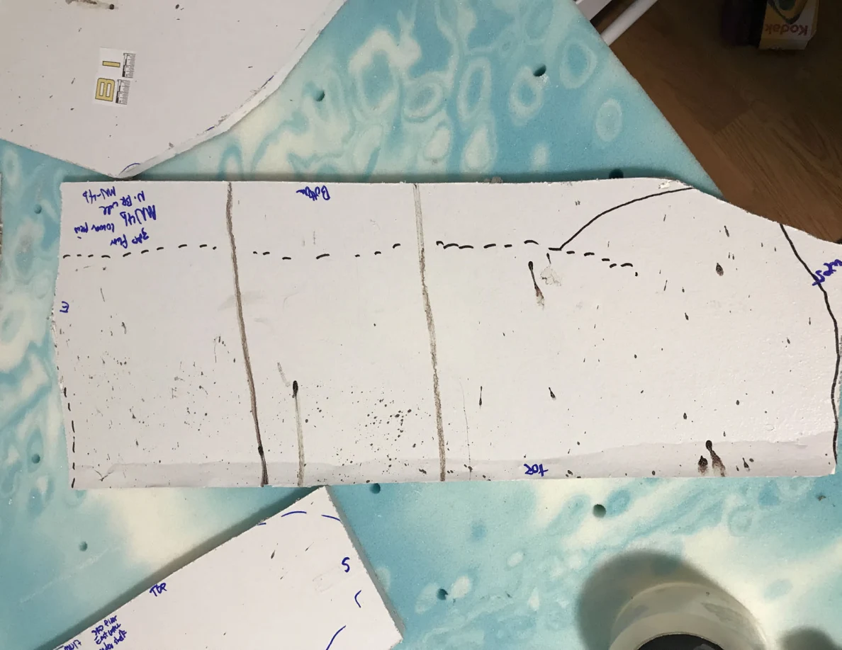 Long white panel section with vertical dark lines, scattered marks and handwritten labels.