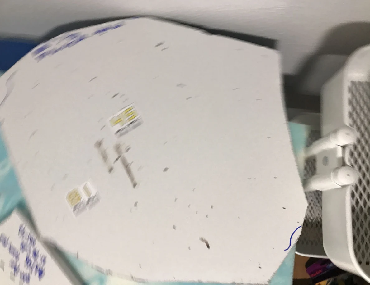 Slightly blurred view of a rounded white panel cutout with dark marks and small labels.