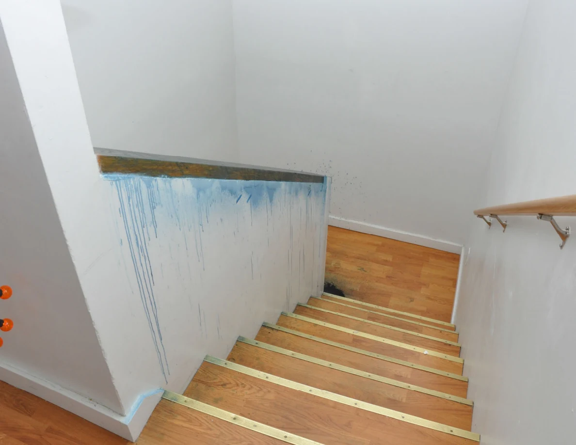 Wooden staircase beside a half-wall with long blue streaks beneath its dark cap.