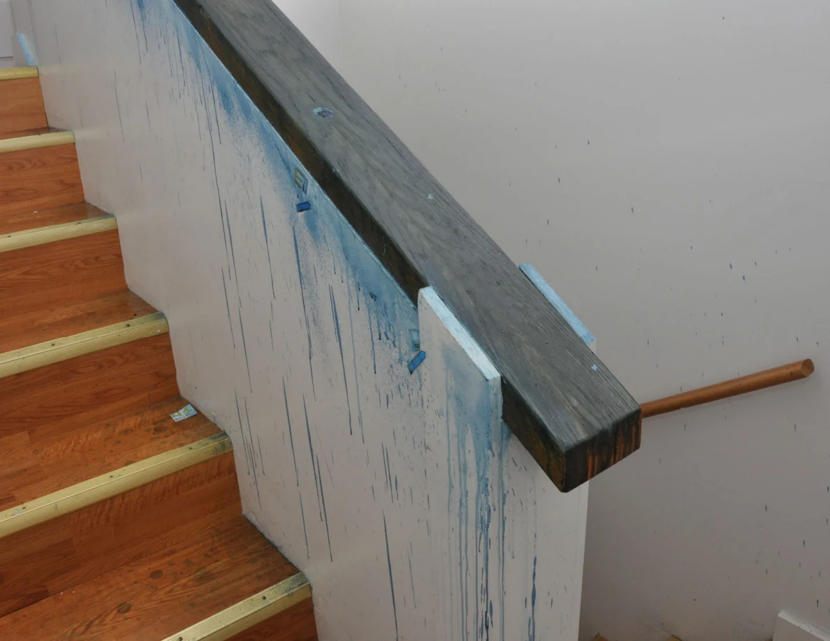 Angled view of stairs and a dark-capped half-wall with long blue streaks.
