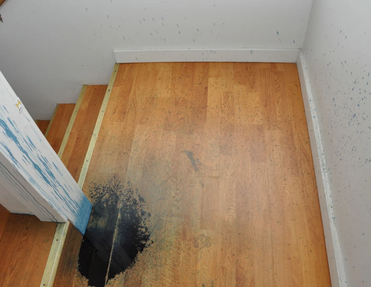 Wooden landing with dark blue patch beside the half-wall and scattered blue marks on walls.