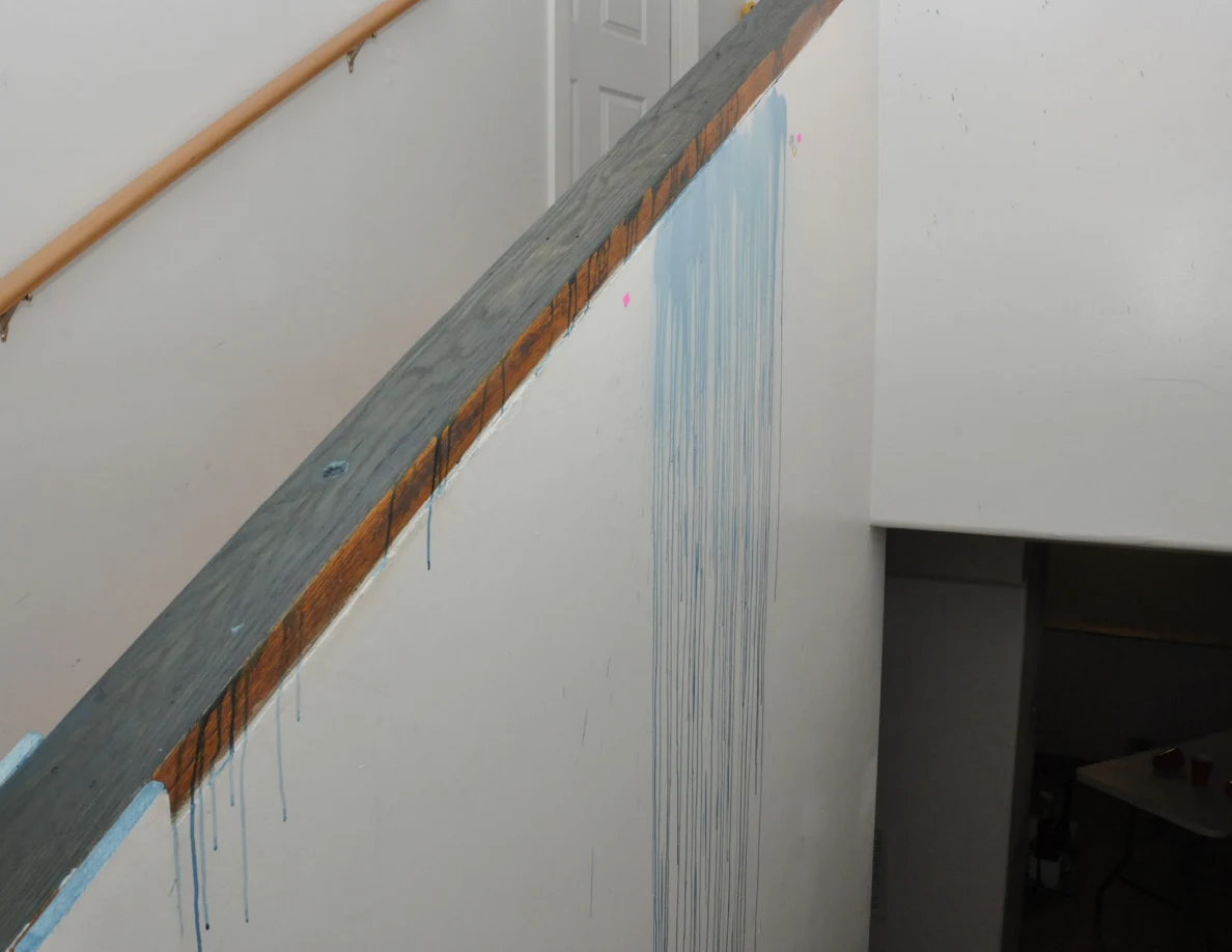 Blue-streaked stair half-wall and dark wooden cap above a lower doorway.