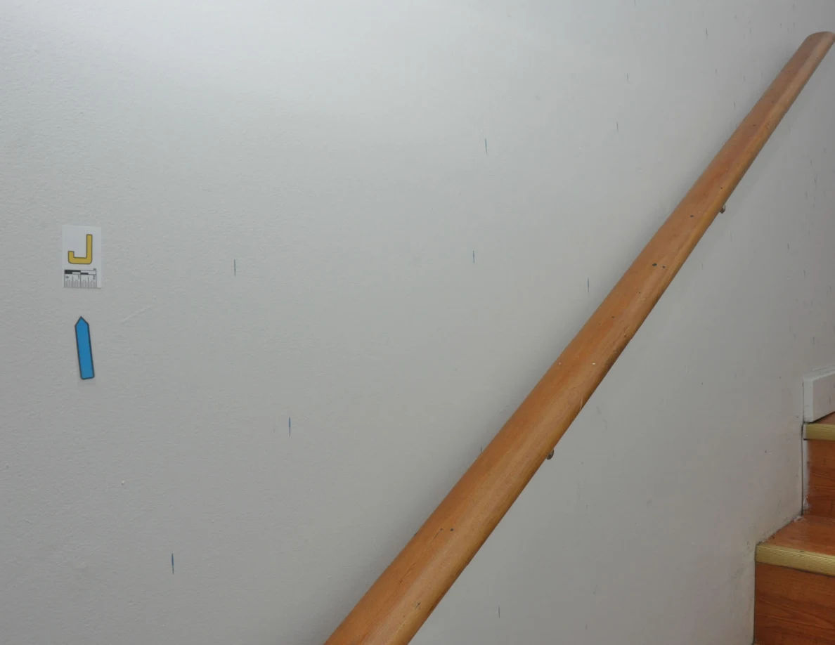 Blue wall marks beside a wooden handrail, with a small letter label and blue arrow.