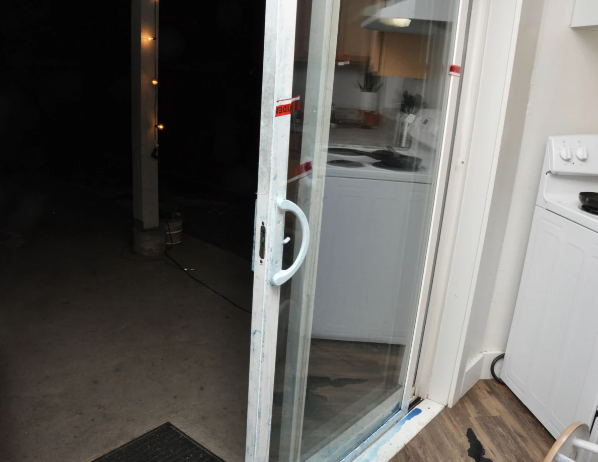 Open sliding glass door with blue-marked white frame beside a stove.