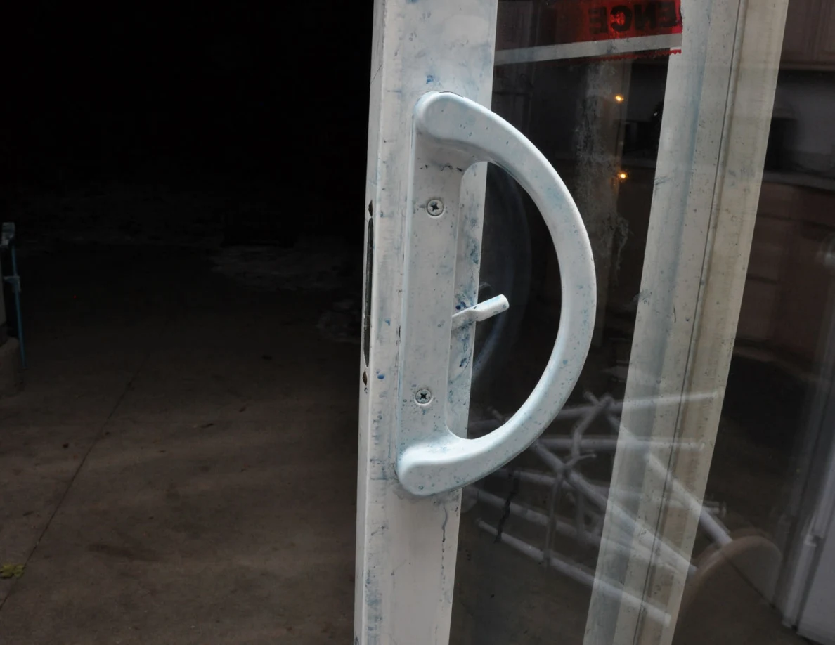 Close view of curved sliding-door handle with blue residue on the handle and frame.