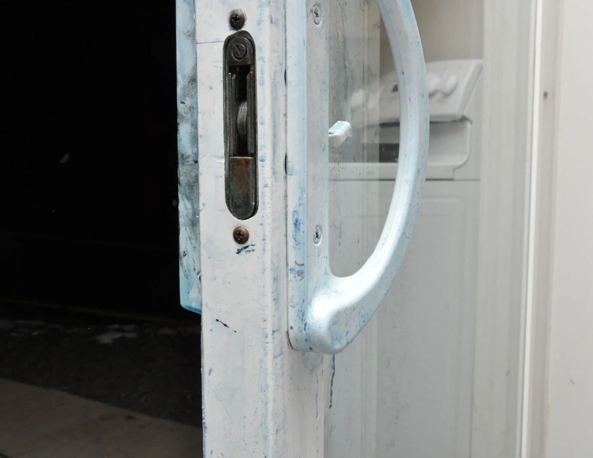 Sliding-door latch and curved handle with blue residue on the frame.
