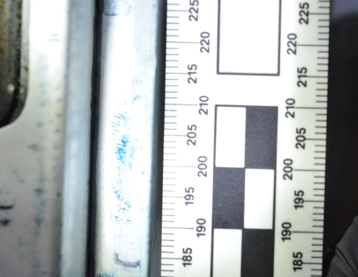 Brighter close view of blue ridge-pattern marks on a white door edge beside a ruler.