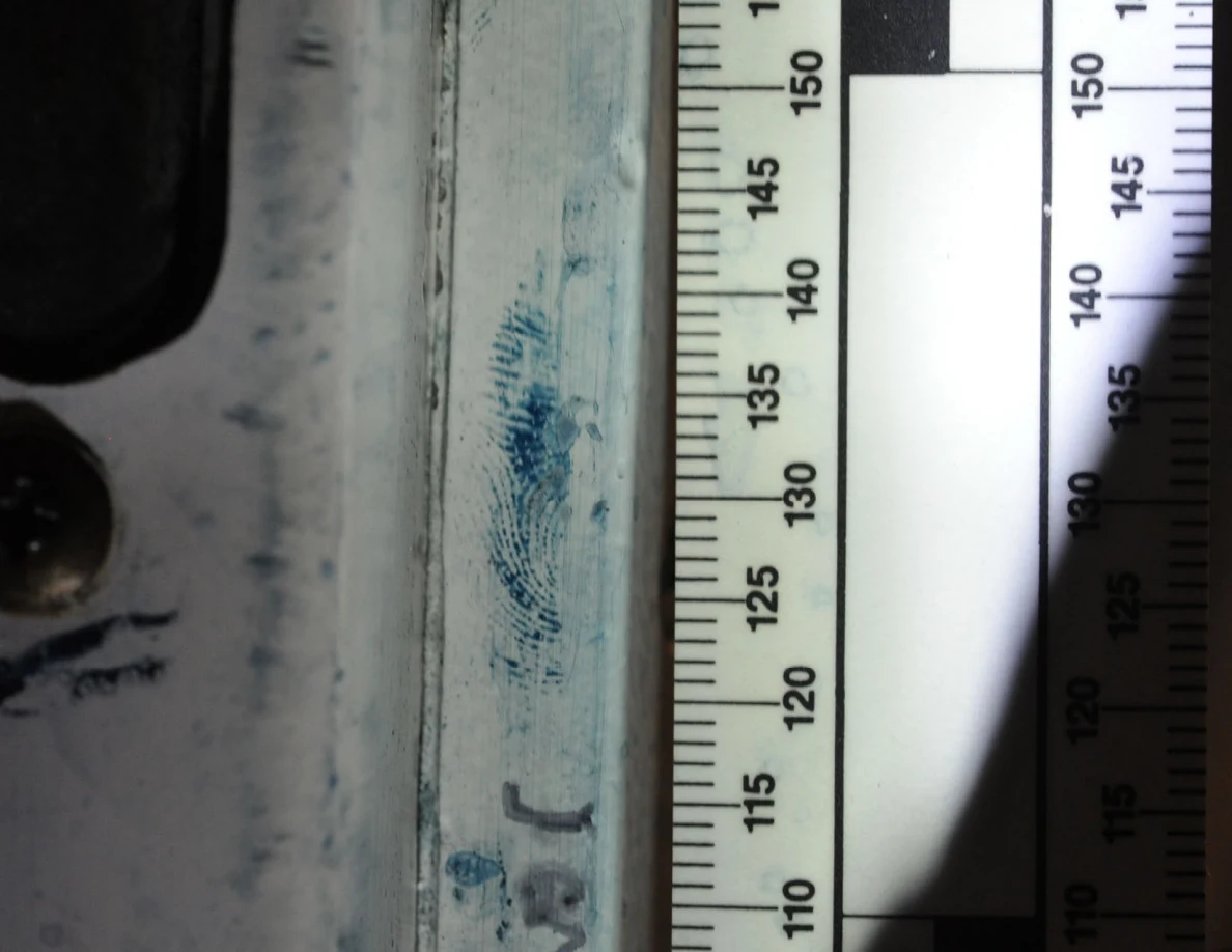 Blue ridge-pattern mark near a door-latch opening beside a measurement scale.