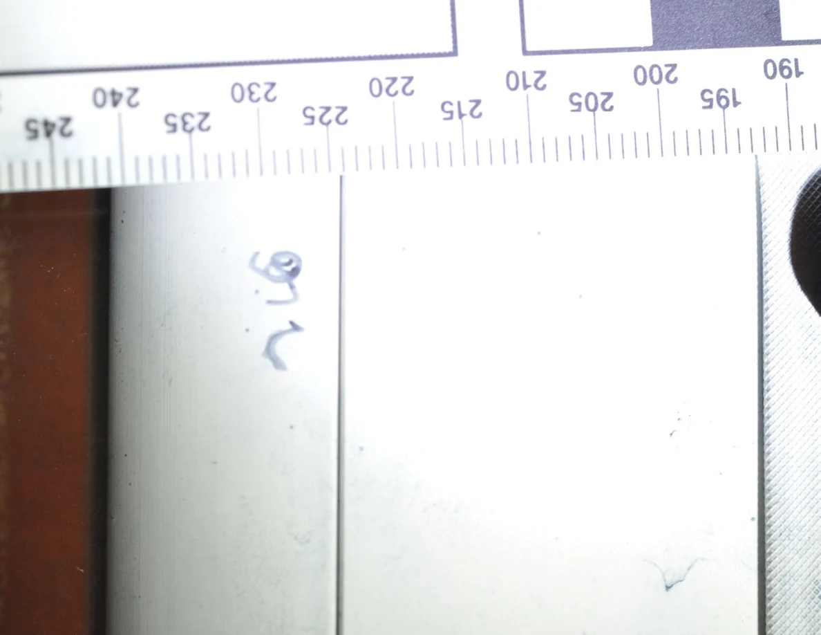 Bright close view of faint blue marks on a white frame beneath a measurement ruler.