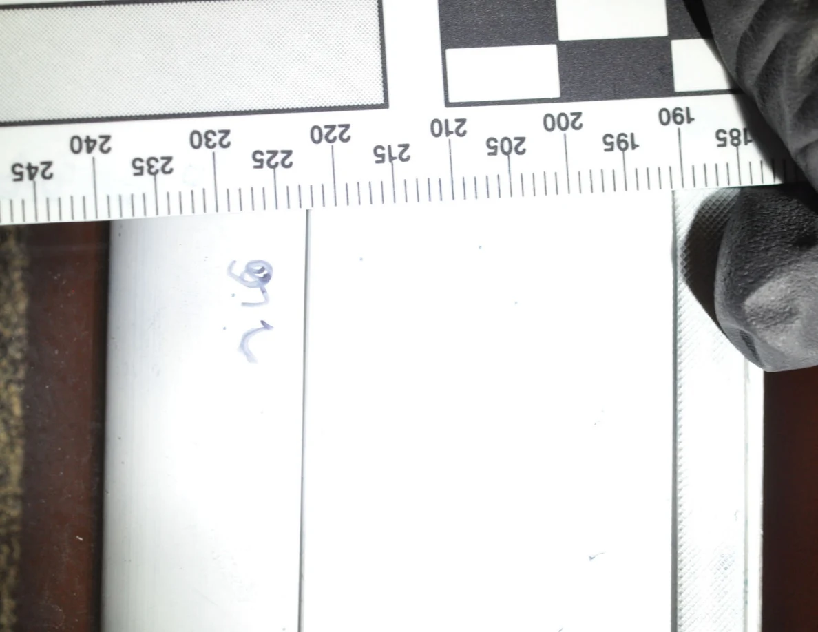 Bright close view of faint blue ridge-pattern marks and handwriting beneath a ruler.