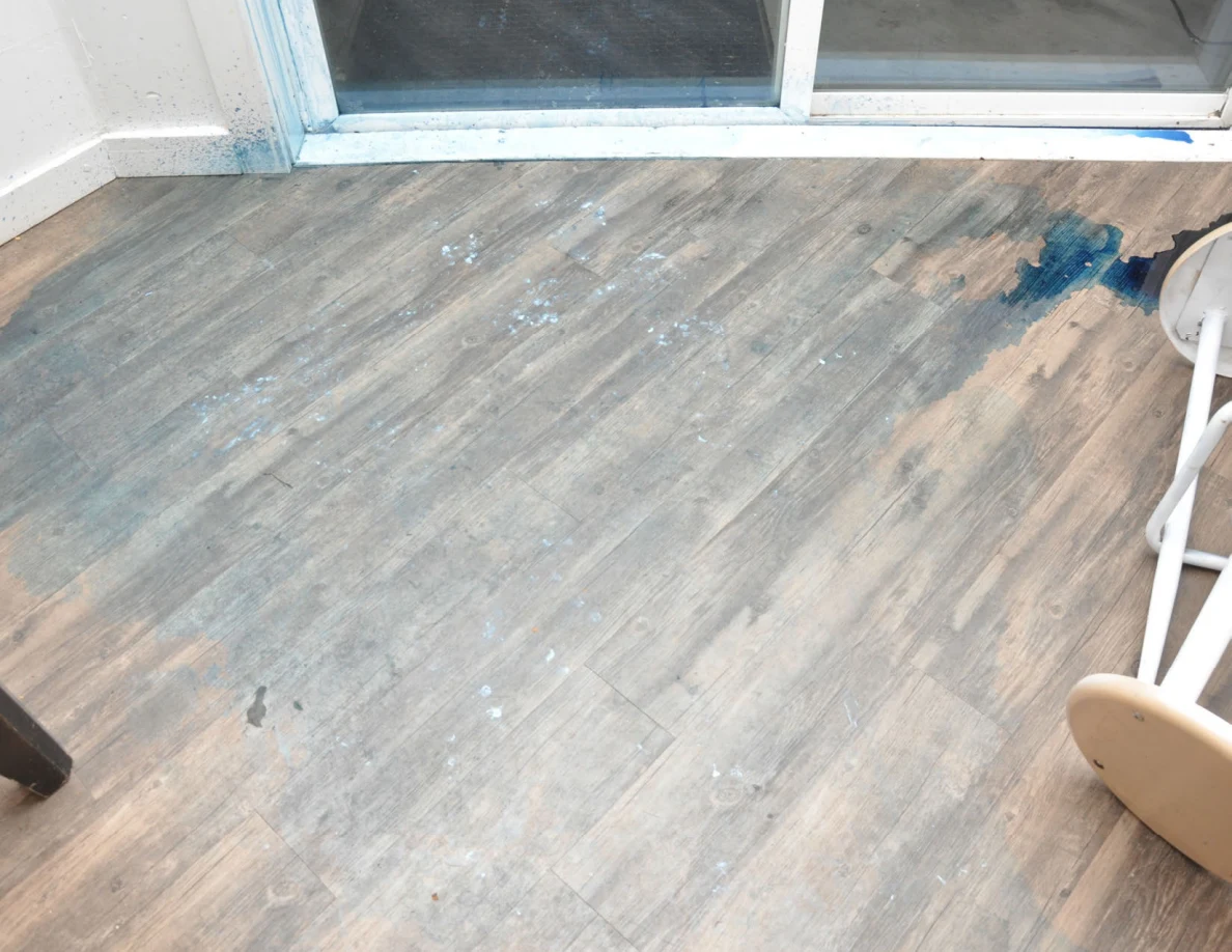 Blue marks and residue across wood-look flooring beside sliding-door track.