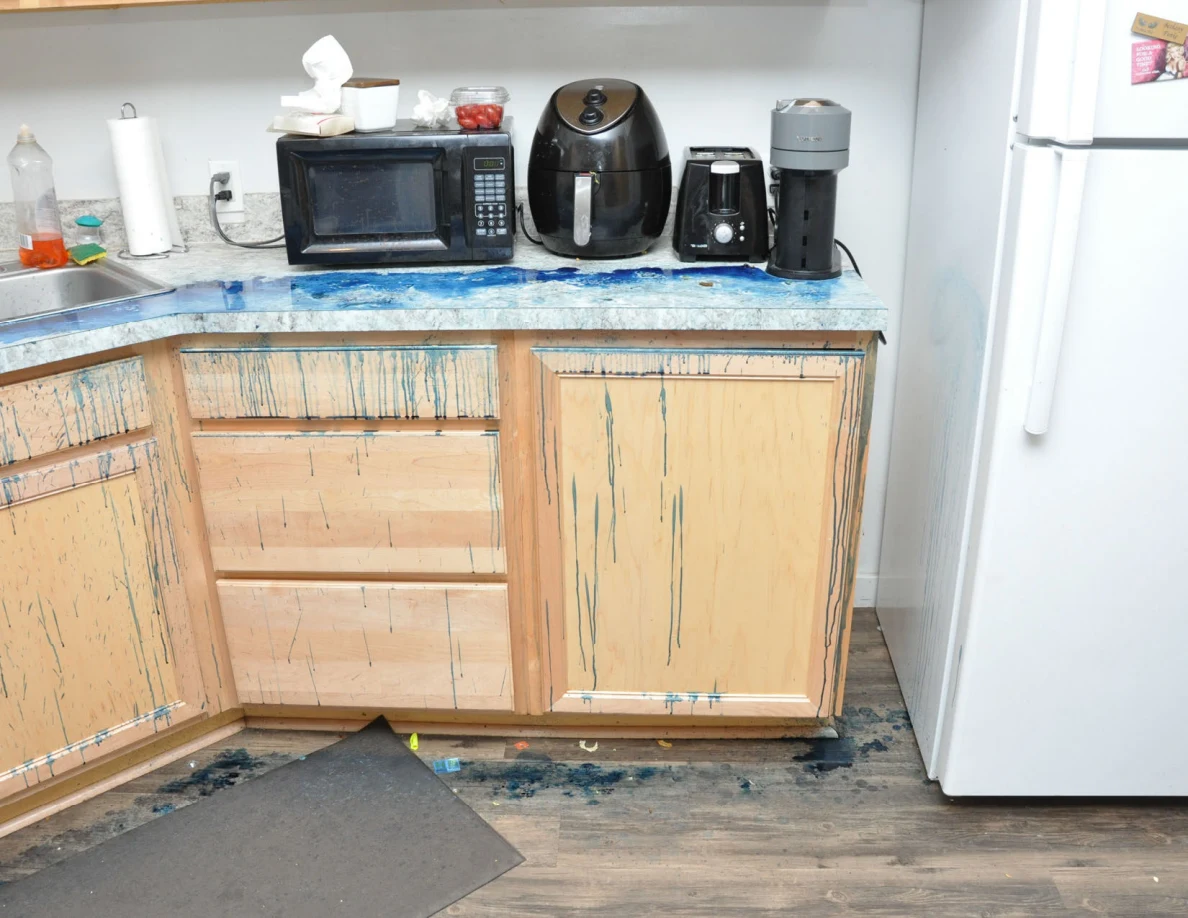 Microwave, air fryer and small appliances above a counter and cabinet fronts streaked with blue residue.