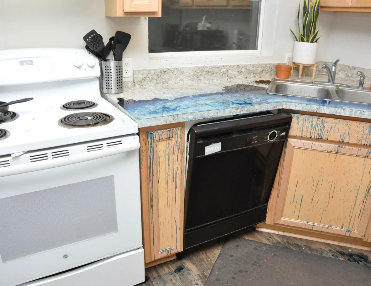 White stove, black dishwasher and kitchen sink beside blue-marked counter and cabinets.