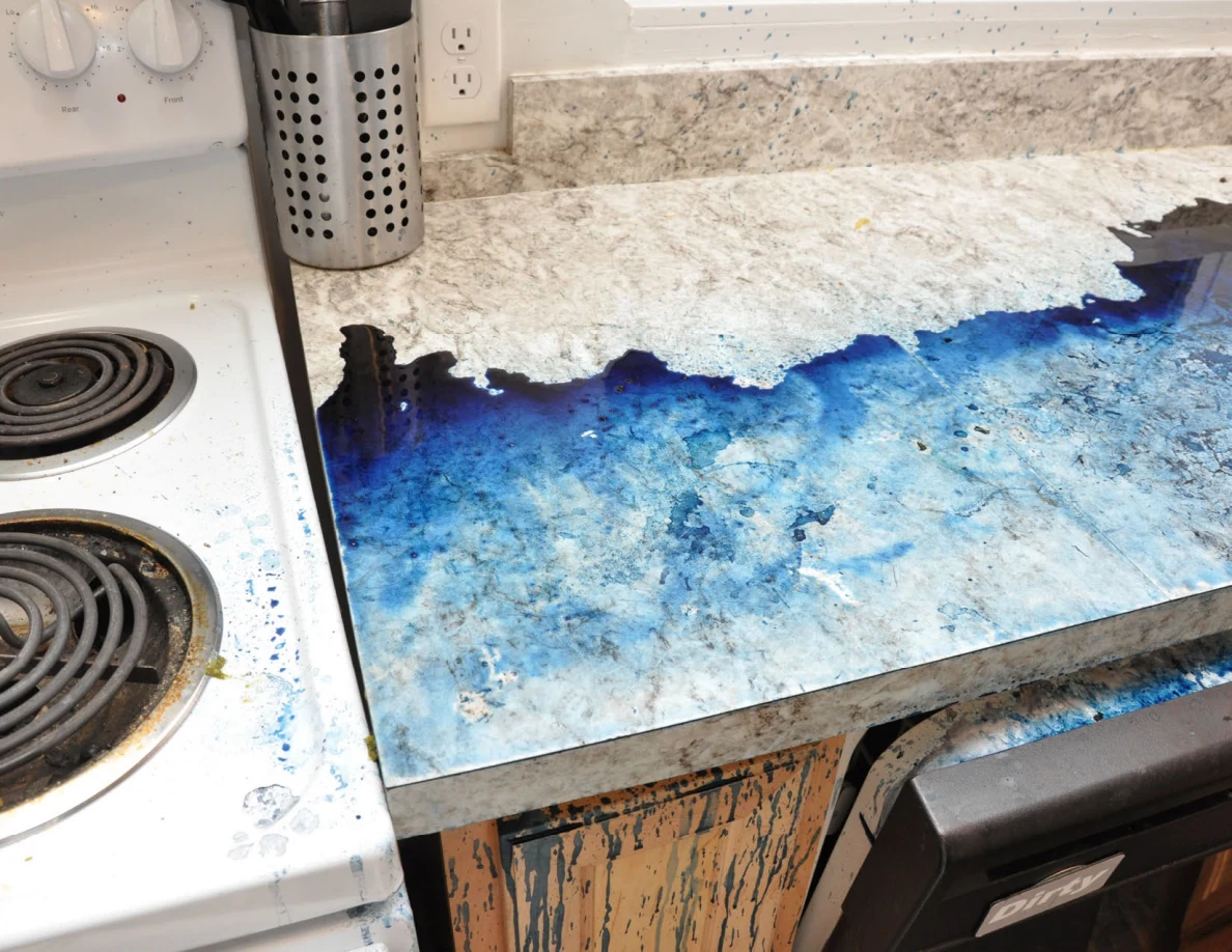 Kitchen counter beside electric stove with broad blue residue and a metal utensil holder.