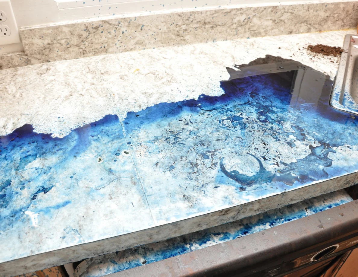 Close view of a countertop covered with blue residue beside the edge of a sink.