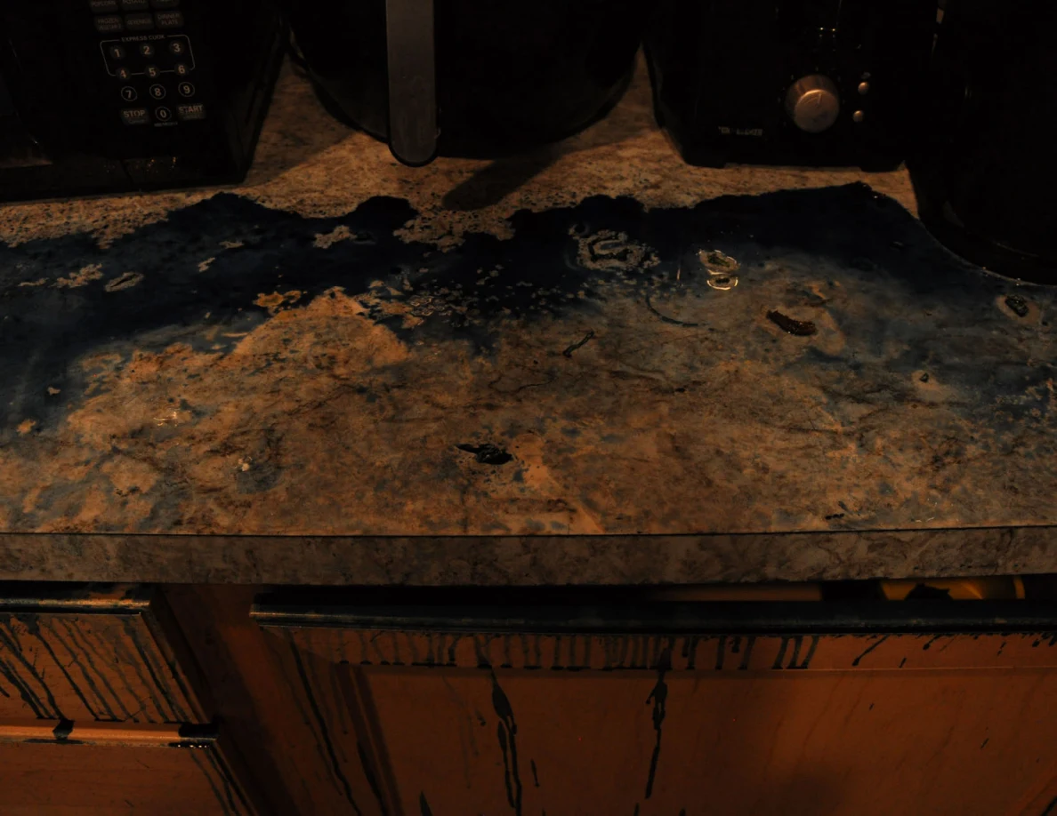 Dim view of dark blue countertop residue below small kitchen appliances.