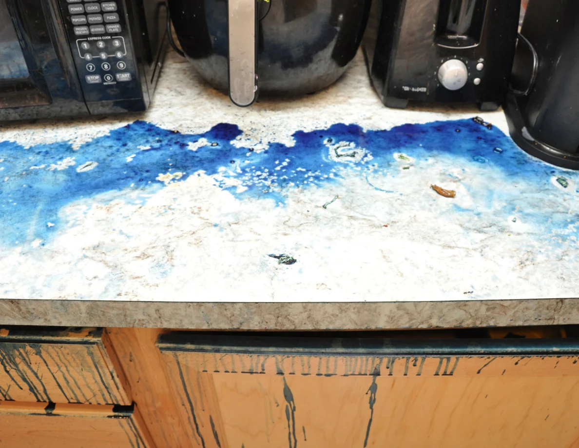Blue-covered countertop beneath an air fryer and blender, above streaked cabinet doors.