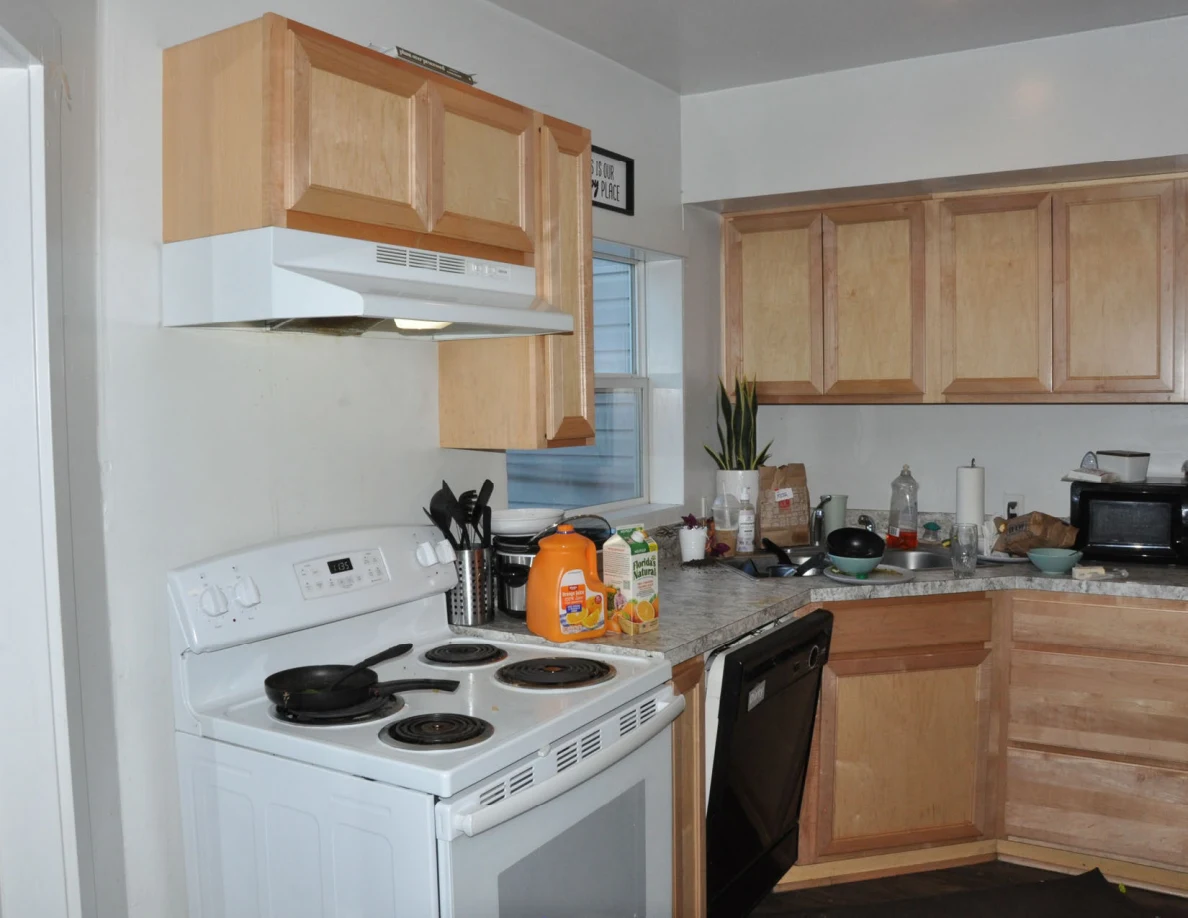 Wide kitchen view with white stove, wooden cabinets, sink and countertop appliances.