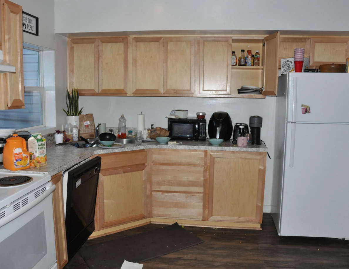 Kitchen with wooden cabinets, white refrigerator, black dishwasher, microwave and countertop appliances.