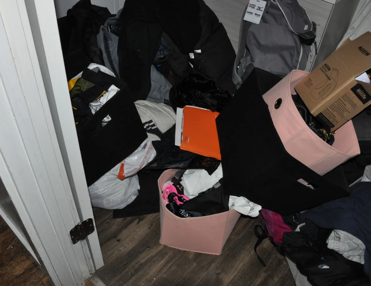 Bags, fabric bins, clothing and a gray backpack crowded together in a small room.