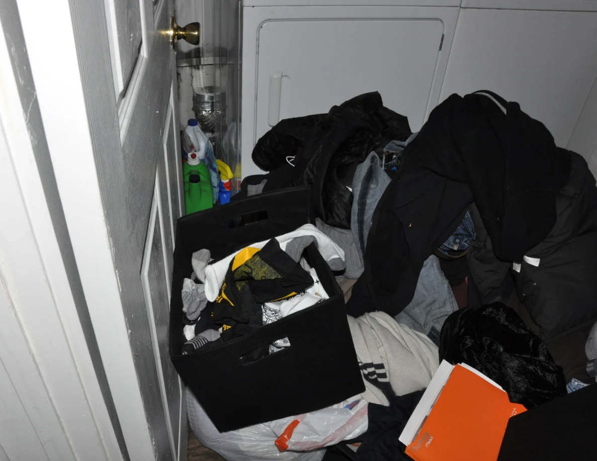 Clothing-filled bins and bags beside cleaning bottles and a white laundry appliance.