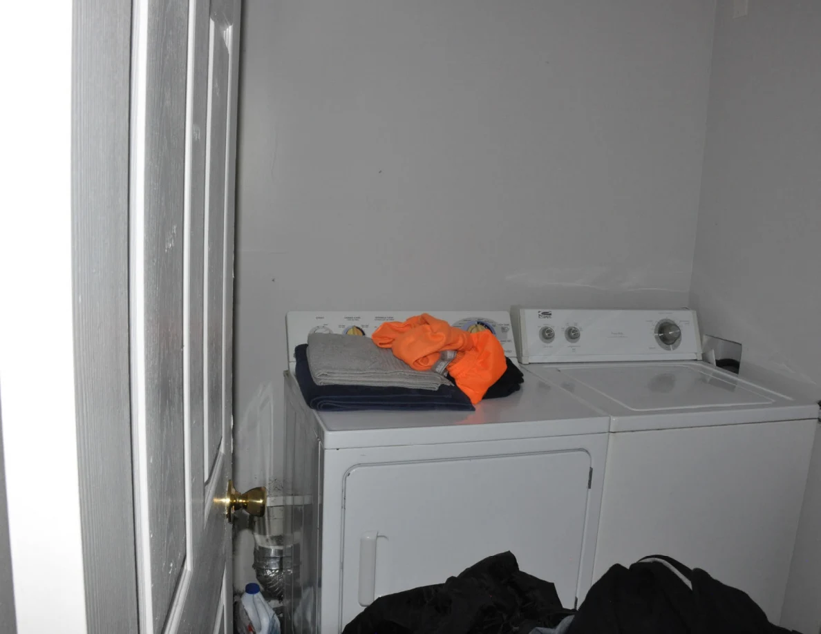 White washer and dryer with folded clothing and orange fabric on top.