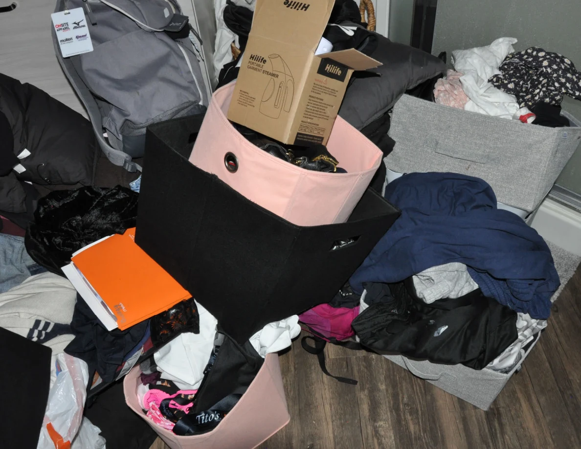 Fabric storage bins filled with clothing and boxes beside a gray backpack.