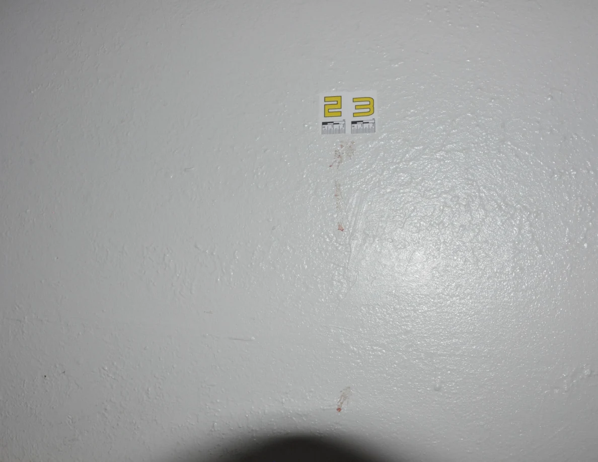 Wider view of label 23 above reddish marks on a pale wall.